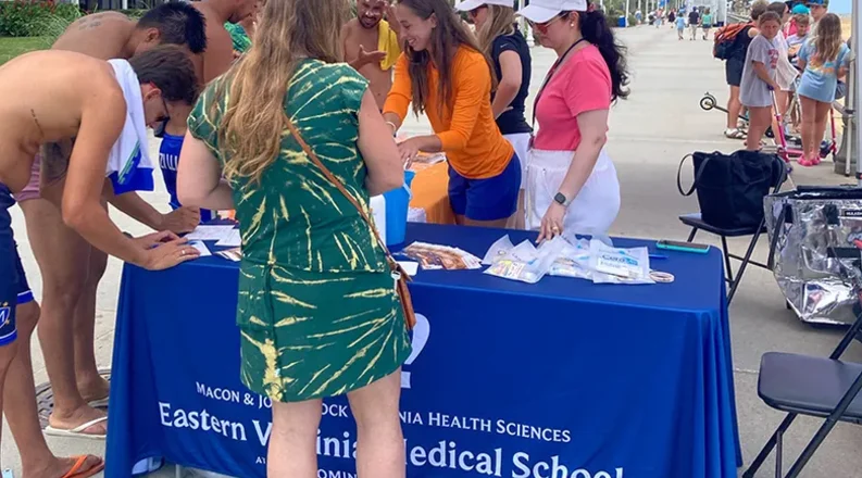 people under a tent handing out sunscreen.