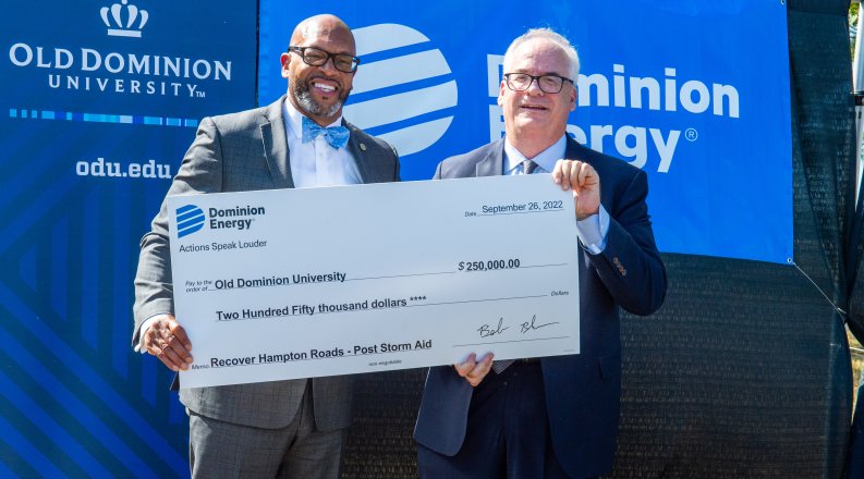 Two men hold a large check for a donation to support resilience research.