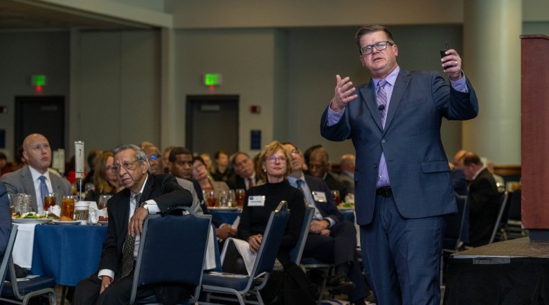A man presents to a group of people in a conference room. 