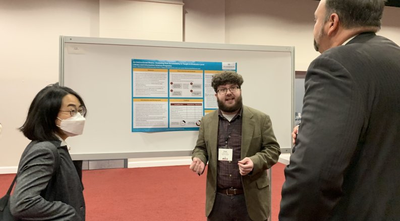 Three people talk in front of a whiteboard.