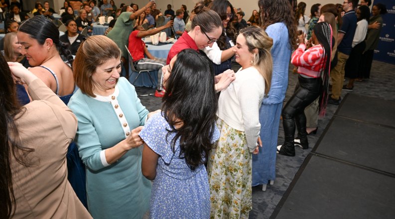 A group of students receives First-Generation Graduate pins during a ceremony.
