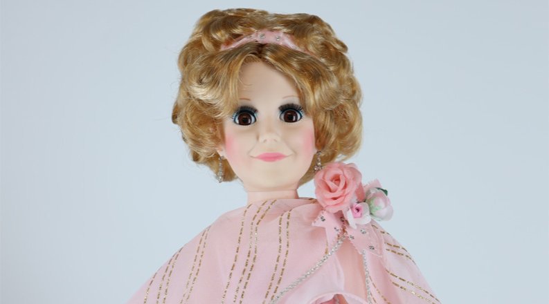 Photo of a doll with a pink dress on. 