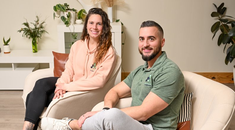 ODU alumni Amanda Bennett and Marc Adams sit in chairs inside their physical therapy business.