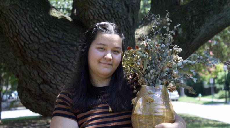 A photo of Kaitlyn Compton with one of her artwork pieces.