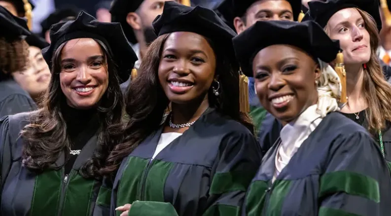Graduating medical students smile during a Commencement cere