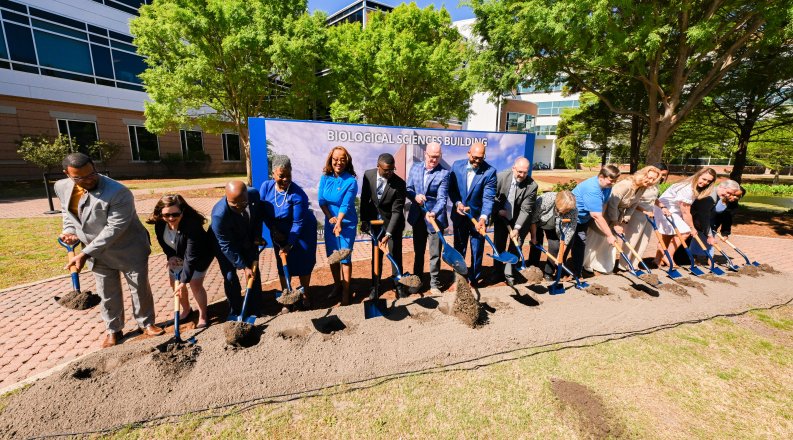 A group of people participate in a groundbreaking event.