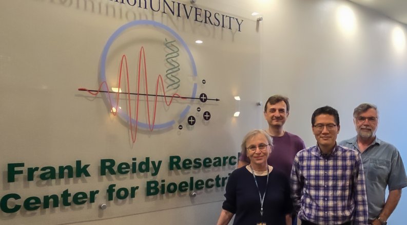 Four faculty members smile for group photo in front of Frank Reidy Research Center for Bioelectrics sign.