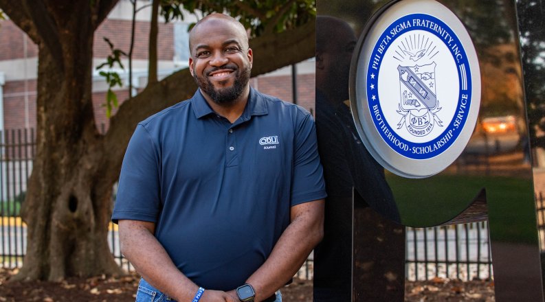ODU alumnus Occasio Gee next to a fraternity monument. 