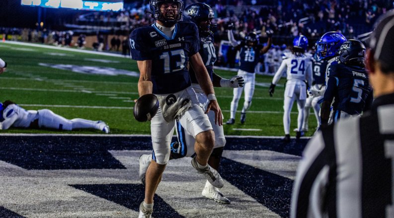 A football player stands in the end zone and celebrates a touchdown. 