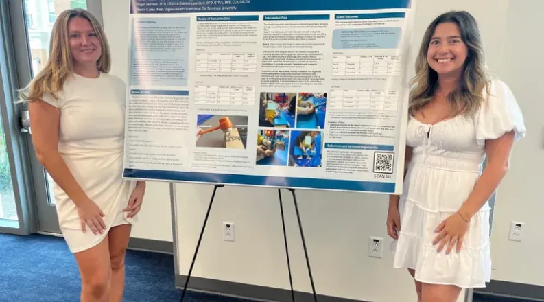 Two individuals stand with a poster detailing an occupationa