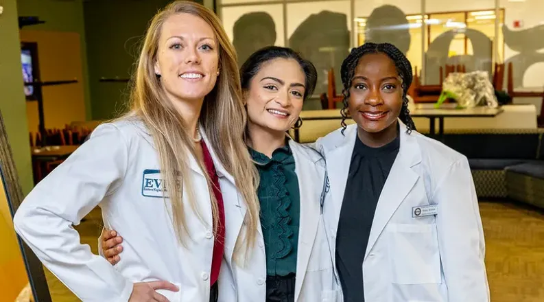 Three female students in white lab coats