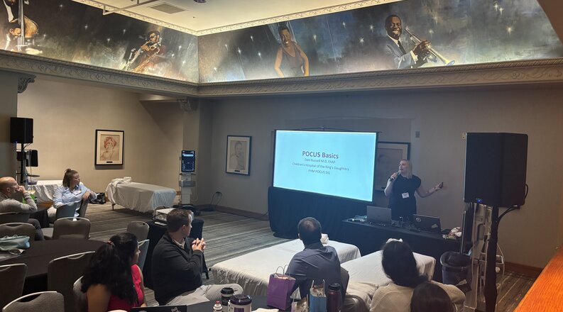 Attendees watch presentation on projector screen at Pediatric Hospital Medicine Conference.