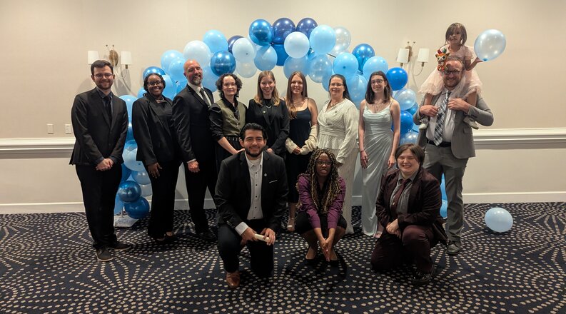 Students in stand in front of a baloon arch