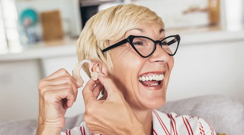 A senior woman with short blond hair and retro black eyeglas