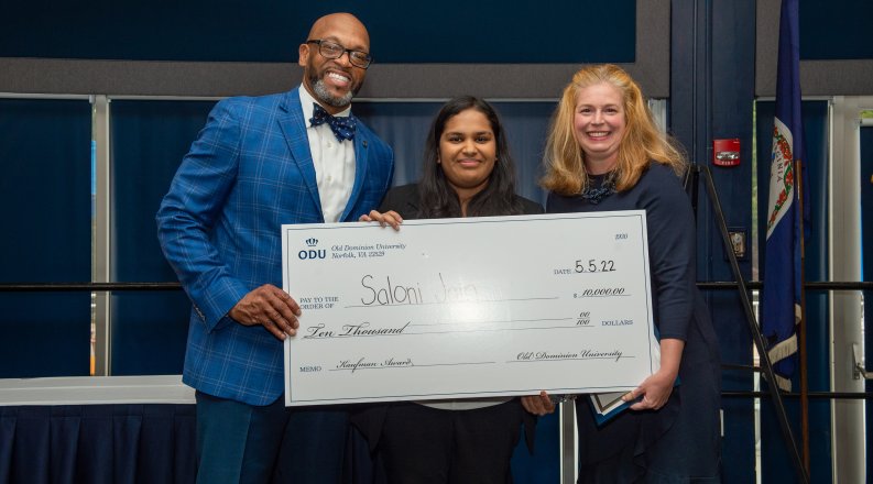 A student holds a big check she received as winner of the Kaufman Award.