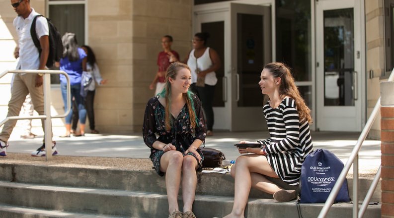 students talking on the steps of a building