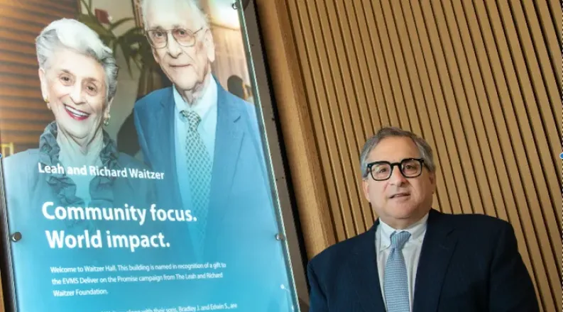 Brad Waitzer standing with a photo of Leah and Richard Waitz