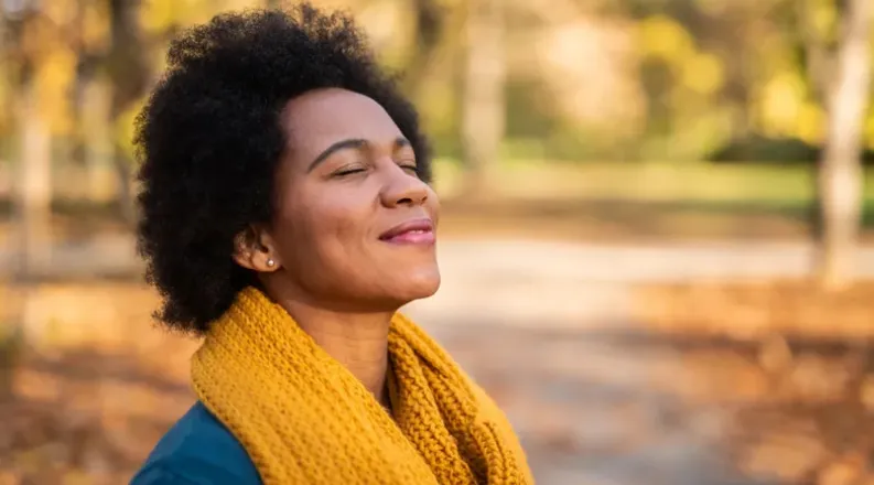 Woman smiling with fall leaves in background