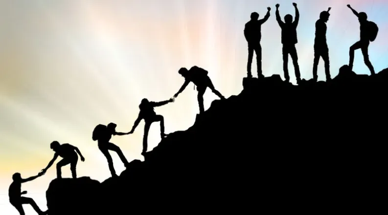 Shadow of people on a mountain helping each other