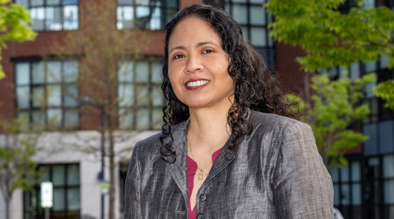 Headshot of woman smiling in front of an academic building