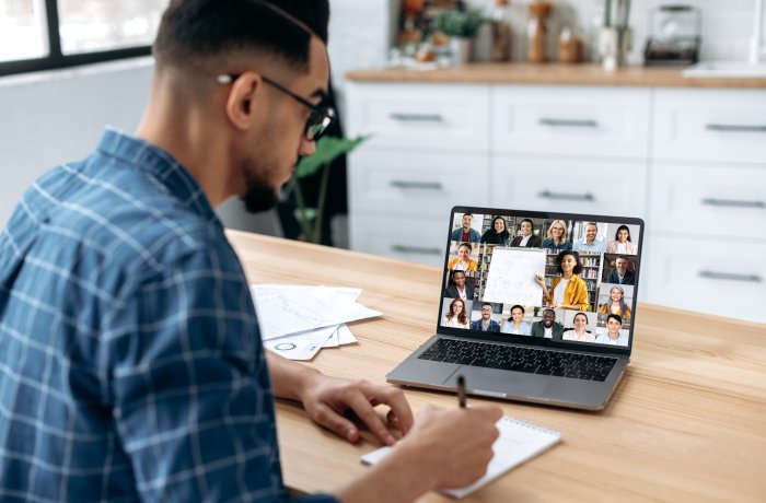 A person in front of a laptop engaging with a group of people online