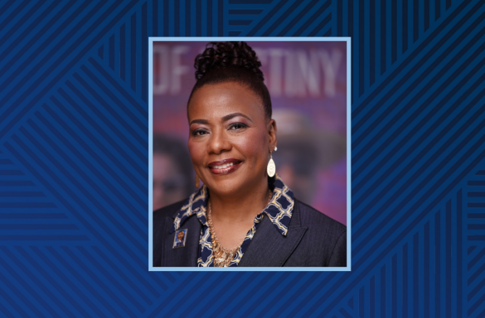 A Black woman poses in front of a purple background.