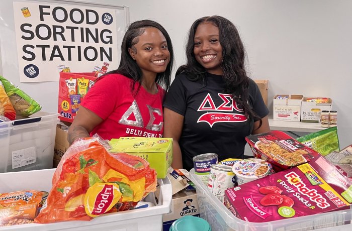 Two female students sort food items for donation.