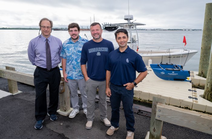 Four men stand in front of boat