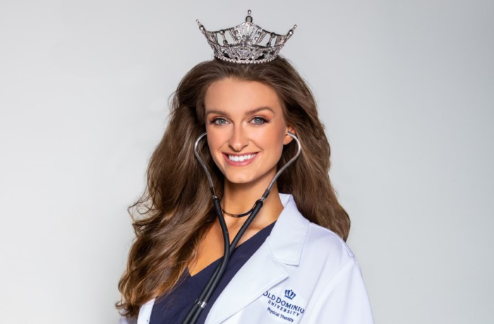 A woman poses wearing a lab coat and a crown.