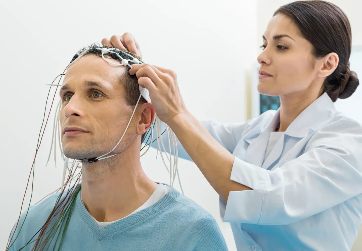 A doctor prepares a patient for an EEG test.