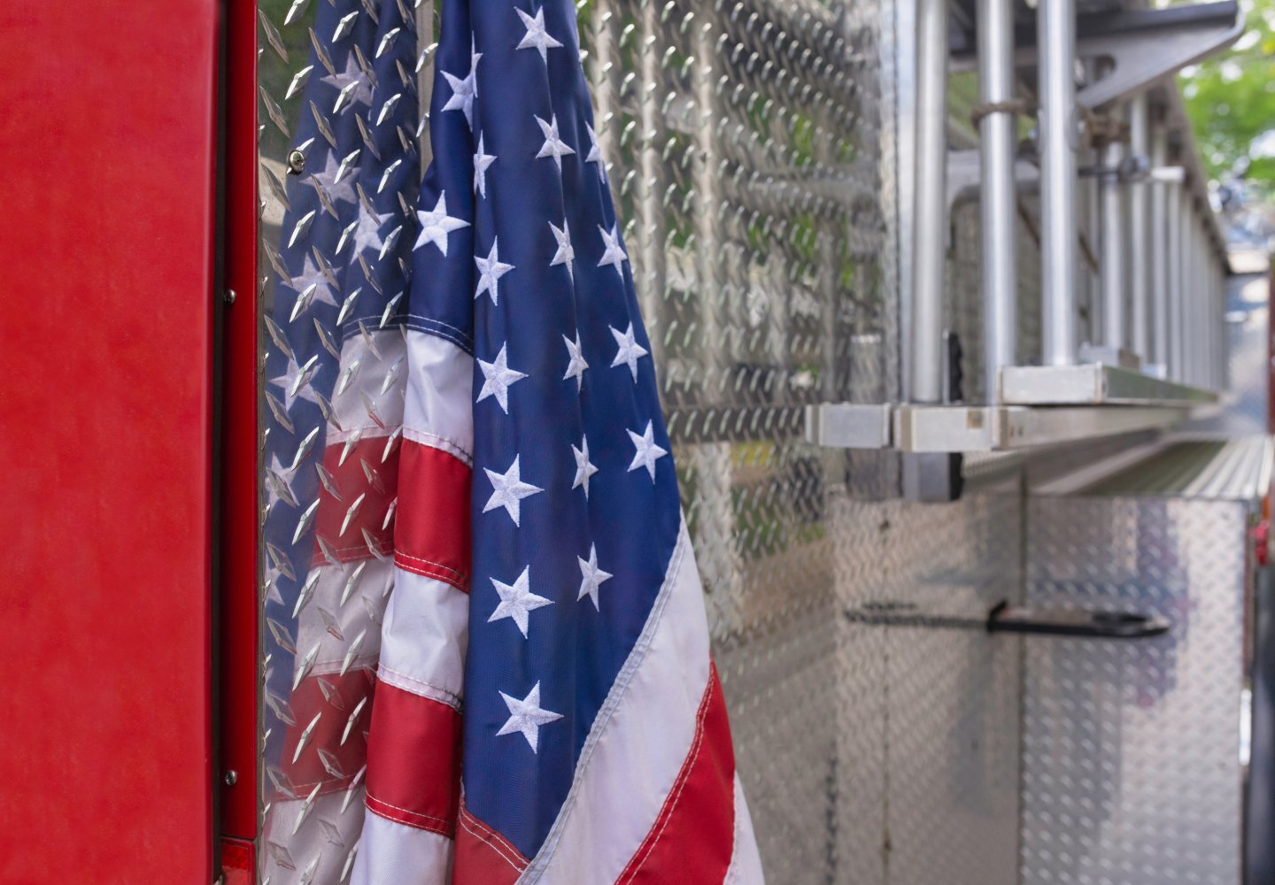 American flag hangs on back of red and silver firetruck.