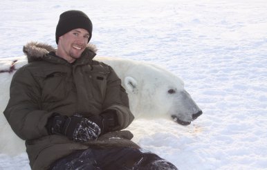 Assistant Professor John Whiteman laying with an adult polar bear