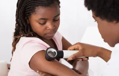A physician looks at a vascular birthmark on a child's arm.