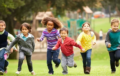 Several children run together in the park.