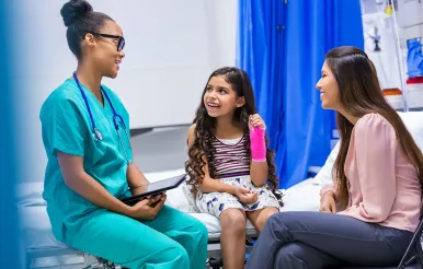 A fellow talks with a patient with a broken wrist and her mo