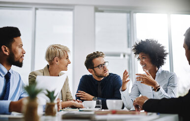A group of professionals participates in a collaborative discussion around a conference table.