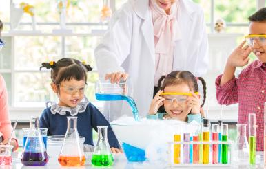 Teacher pour chemicals into glass bowl in lab.