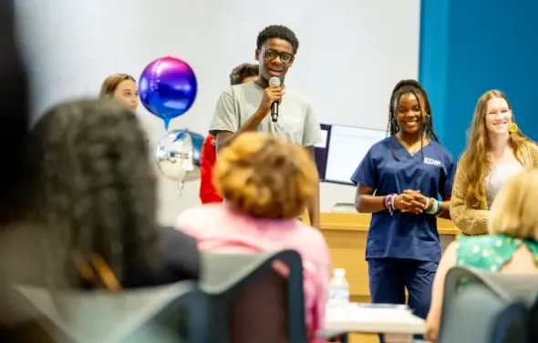 HSA students with balloons, giving a presentation with a mic