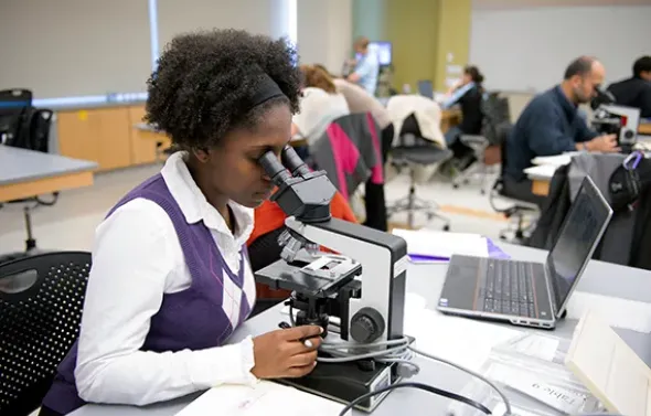 A student studies a sample under a microscope.