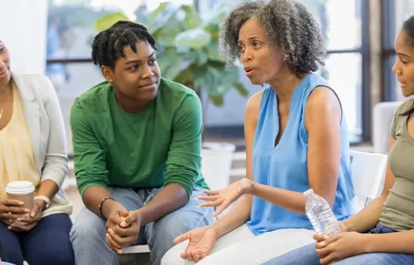 Group of parents listen to counselor discuss teenage issues.