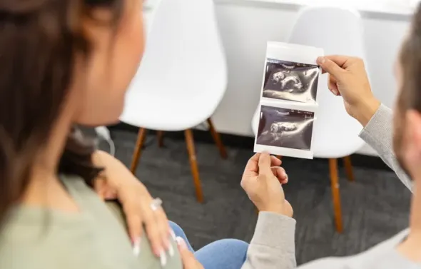 A view over the shoulders of an unrecognizable expectant cou