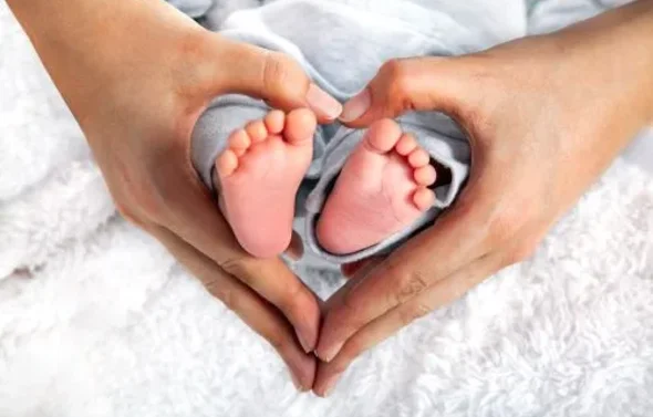 Hands forming a heart around two baby feet