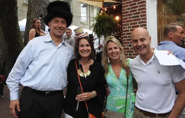 A group of four people in hats pose for a photo together. An