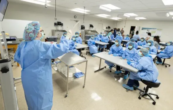 A classroom full of HSA students in blue lab coats and masks