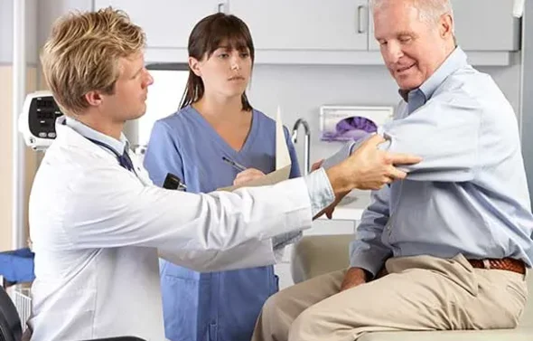 A physician examines a patient's arm while a student observe