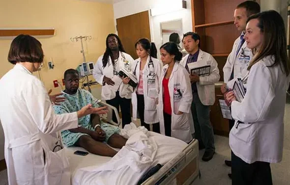 A team of residents visits with a patient
