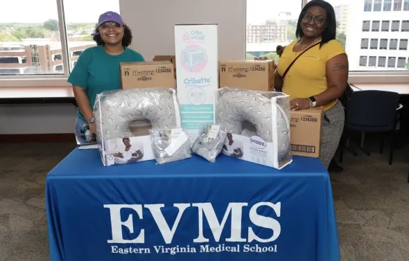 Two female staff members stand next to a display table