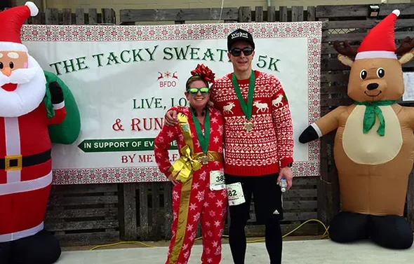 Runners in holiday attire smile for a photo at the Tacky Swe
