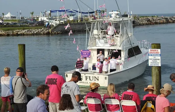 Wine, Women and Fishing attendees watch from the dock as a b