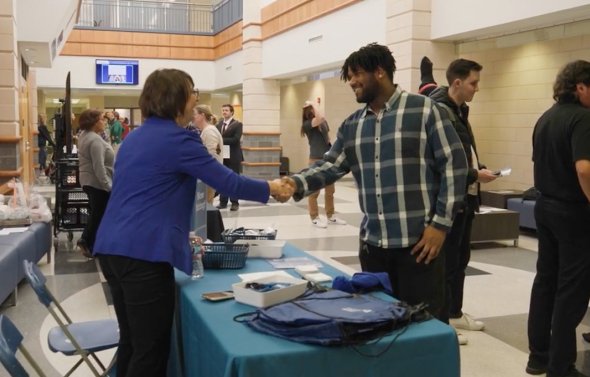 Accountancy professor greets student in School of Business lobby.